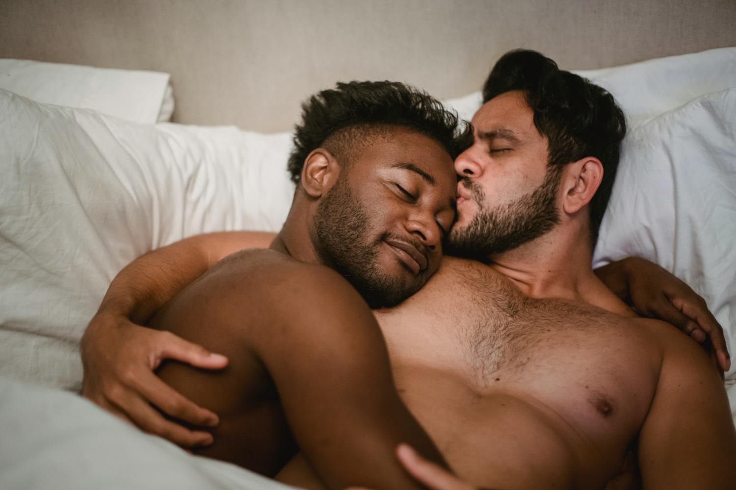 An affectionate couple cuddles in bed, sharing a loving, intimate moment.