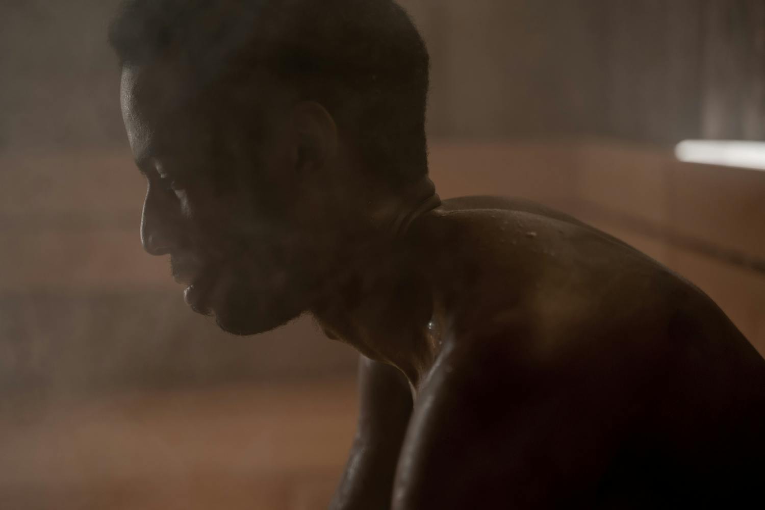 Side view of an adult man relaxing in a steamy sauna, focusing on wellness and self-care.